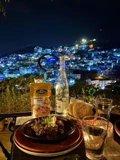 Kemasan Permen Jahe Padjajaran di meja makan malam dengan latar kota biru Chefchaouen, Maroko